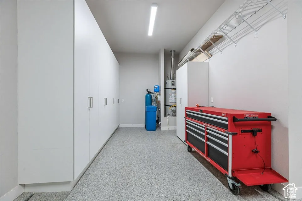 Epoxy-coated flooring, built-in storage cabinetry, overhead wire shelving, wall-mounted water heater, and water filtration system