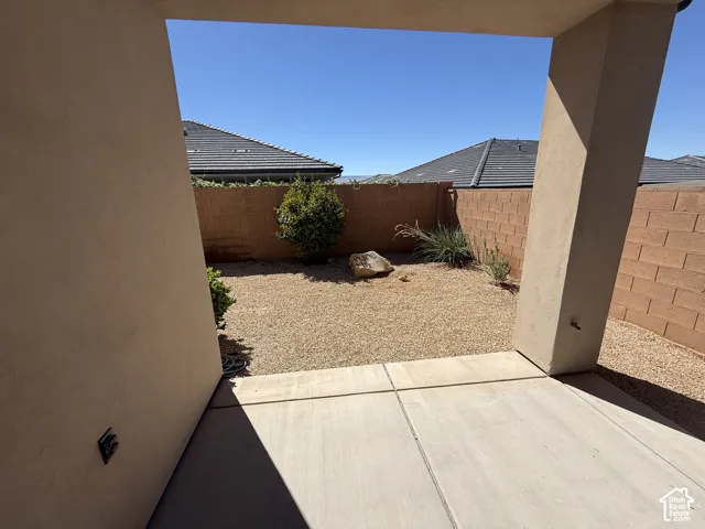 Covered concrete patio featuring xeriscaped grounds, masonry perimeter wall, and established desert landscaping