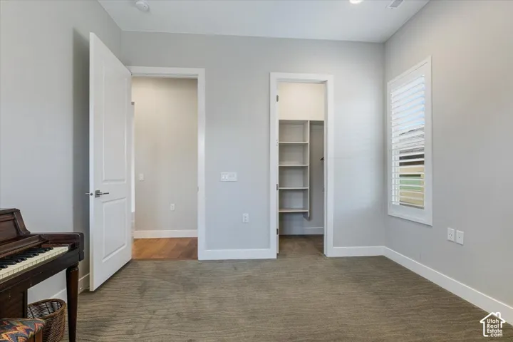 Neutral wall color, recessed lighting, window with plantation shutters, built-in closet shelving, and wood-finish flooring in an adjacent space
