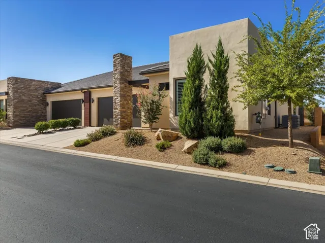 Contemporary exterior featuring stucco siding, stone accents, a dual-car garage, and landscaped xeriscape
