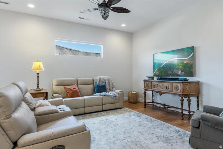 Recessed lighting, wood-finish flooring, a linear horizontal window, and a ceiling fan with integrated lighting