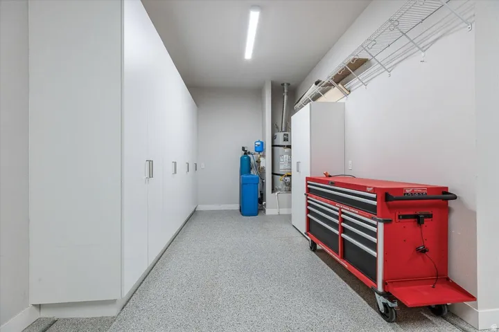 Epoxy-coated flooring, built-in storage cabinetry, overhead wire shelving, wall-mounted water heater, and water filtration system