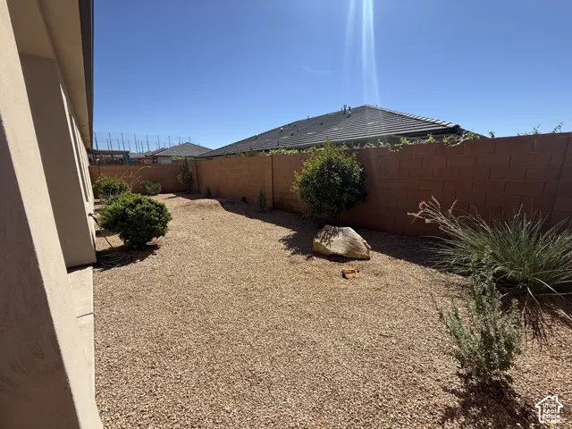Side yard featuring gravel landscaping, mature desert shrubs, a decorative landscape boulder, and a masonry perimeter wall