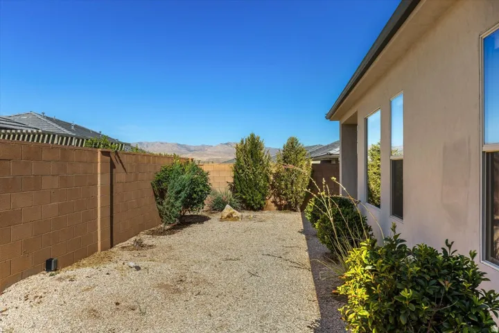 Stucco exterior with multiple windows, gravel landscaping, and mature shrubbery
