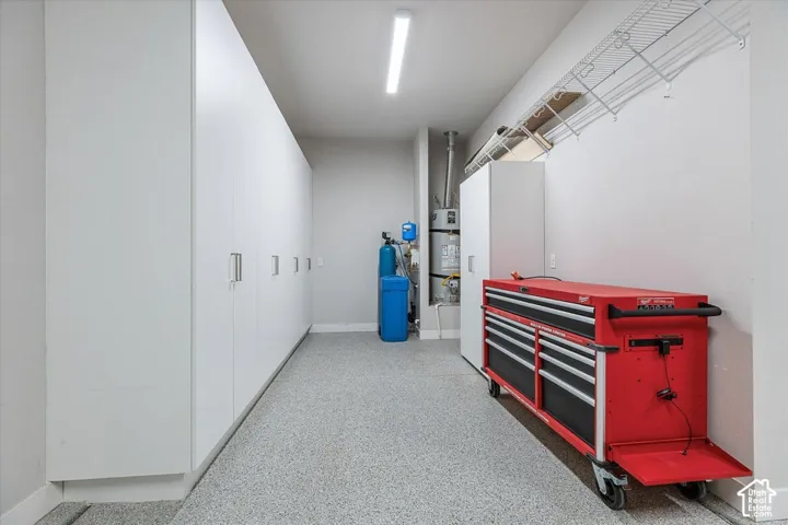 Epoxy-coated flooring, built-in storage cabinetry, overhead wire shelving, wall-mounted water heater, and water filtration system