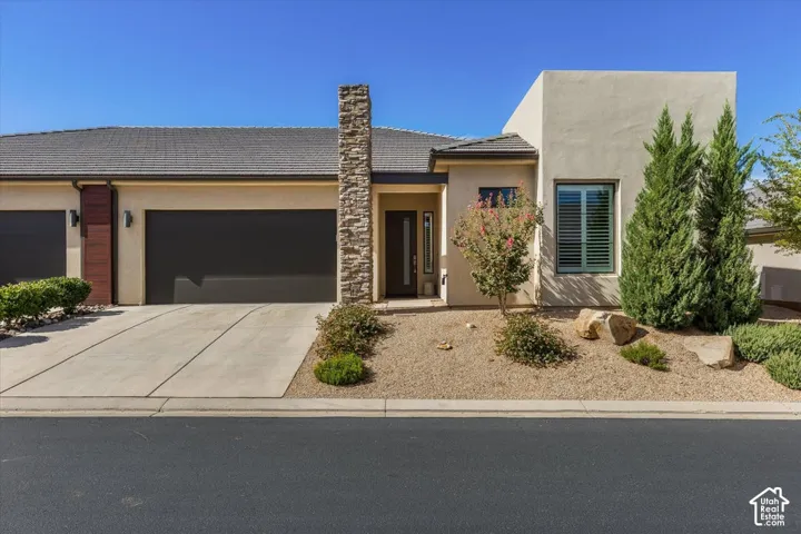 Contemporary stucco exterior with a tiled roof, stone pillar accent, and a single-panel garage door