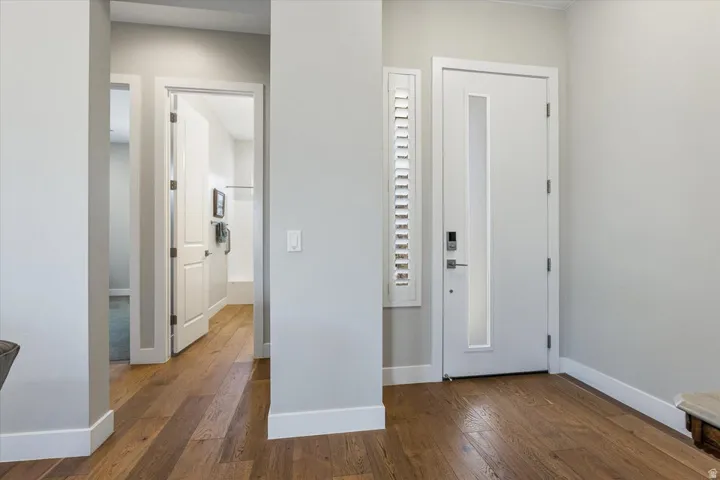 Wood-finish flooring throughout, bright white walls, and contemporary doors with integrated vertical lites