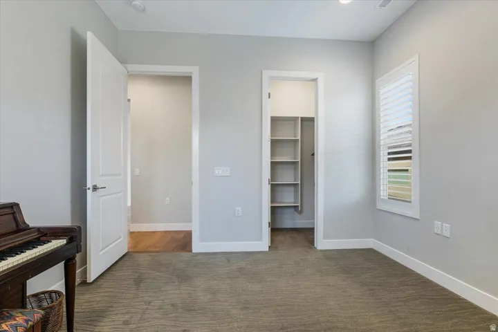 Neutral wall color, recessed lighting, window with plantation shutters, built-in closet shelving, and wood-finish flooring in an adjacent space