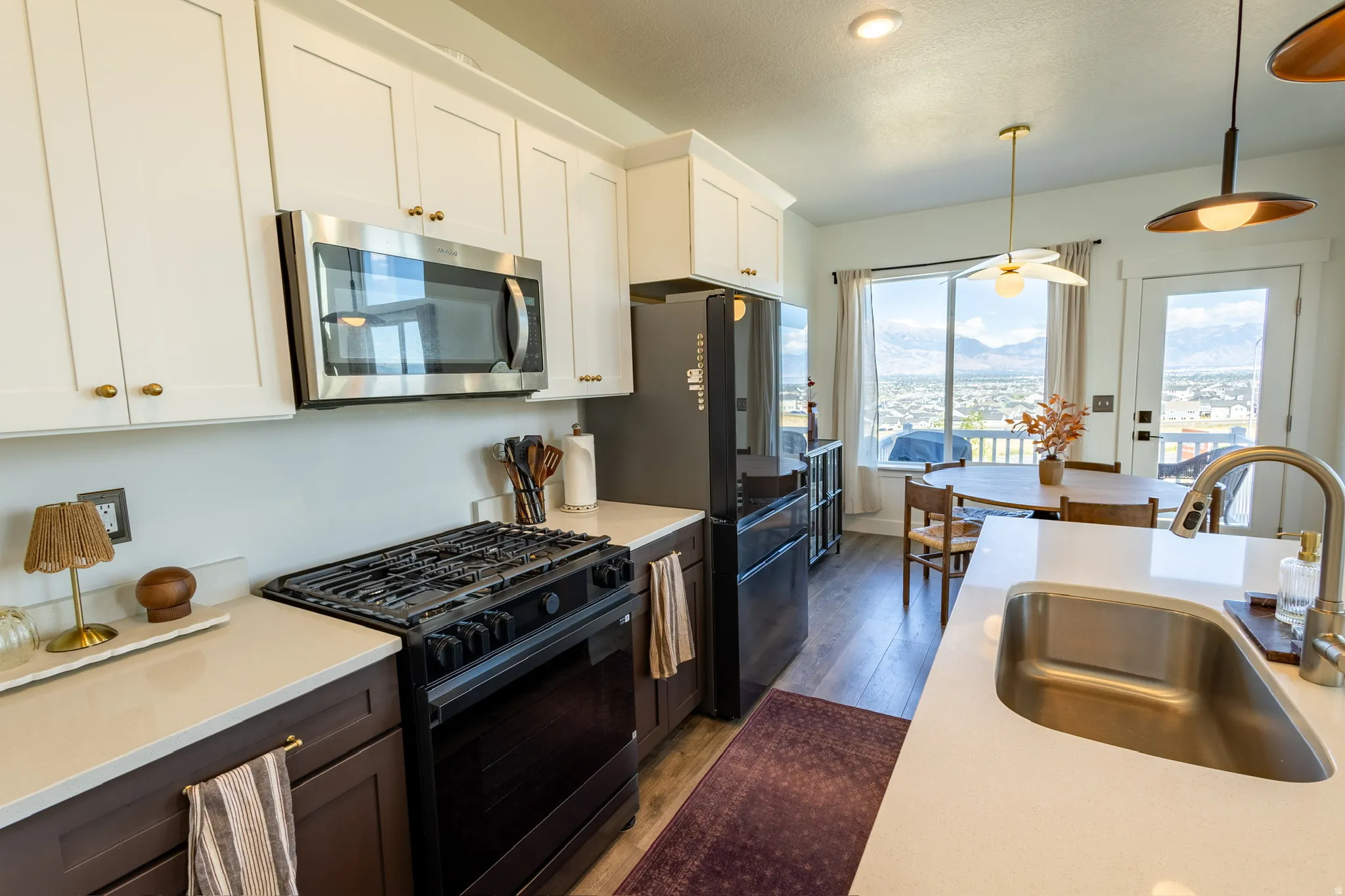 Kitchen featuring stainless steel appliances, white upper cabinetry with brass hardware, a gas range, and a single basin stainless steel sink