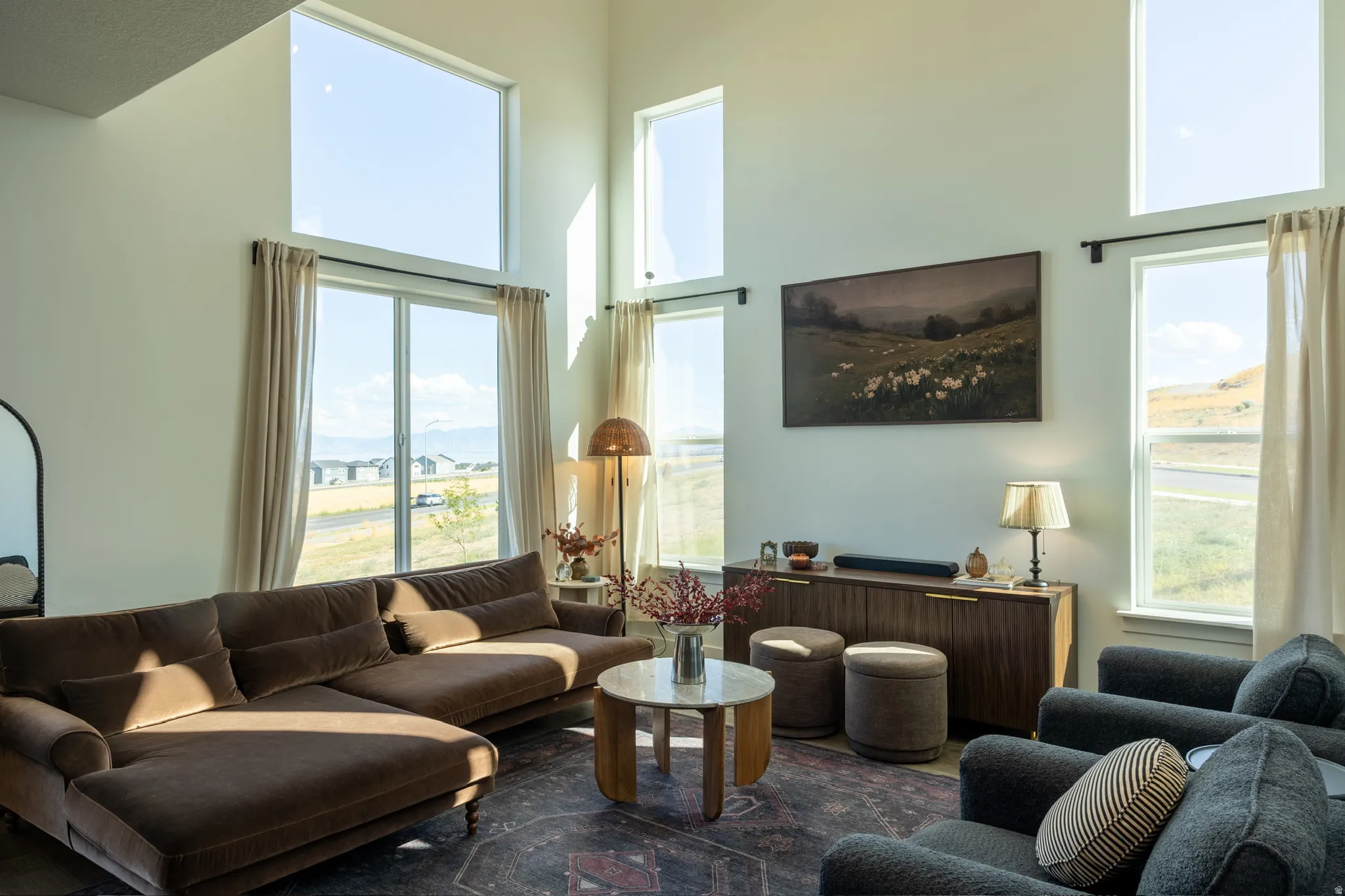 Double-height ceiling, large windows, sliding glass door, wall-mounted display, wood-finish console cabinet