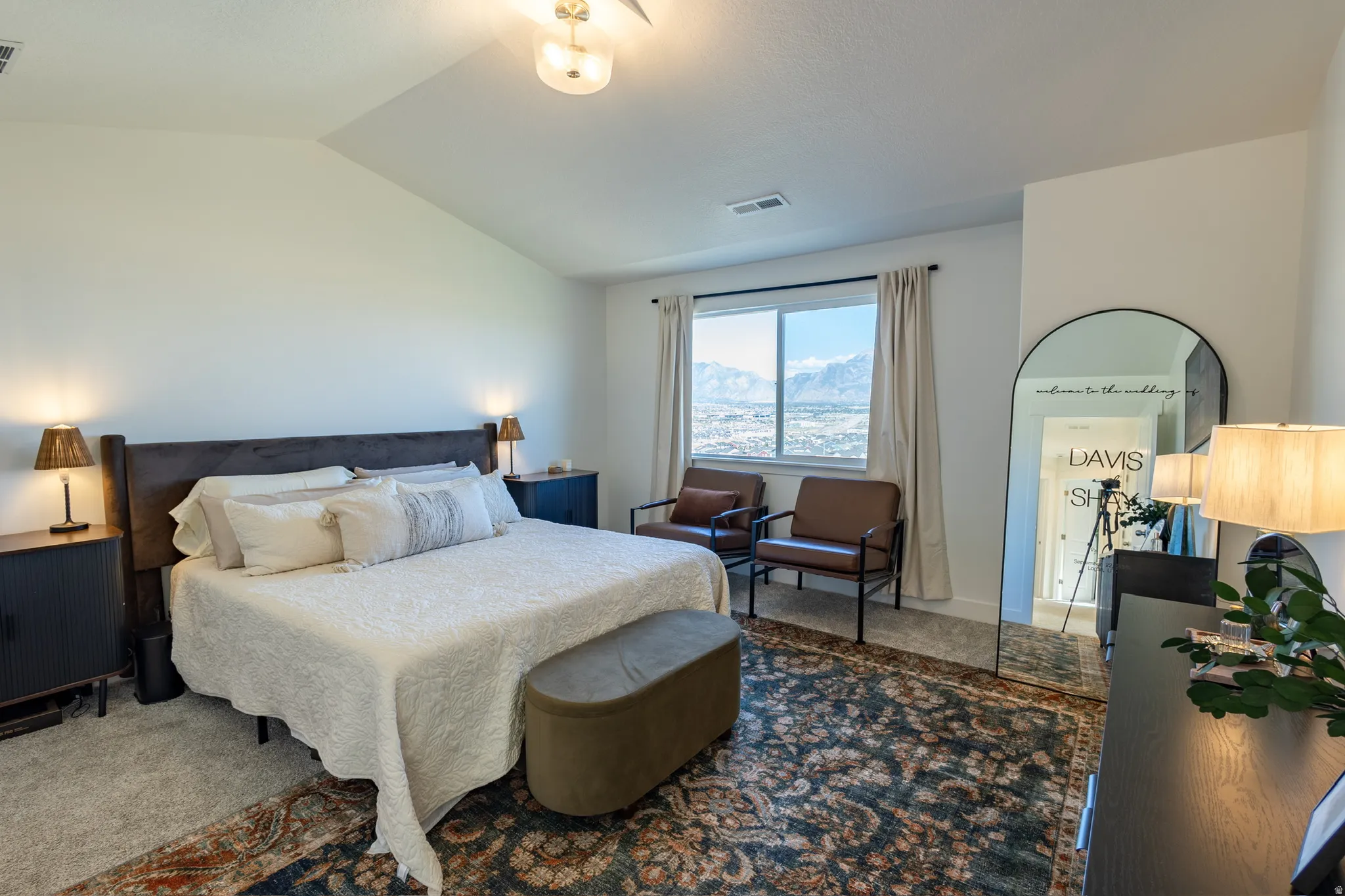 Vaulted ceiling with an attached light fixture, window with mountain scenery, and carpet flooring