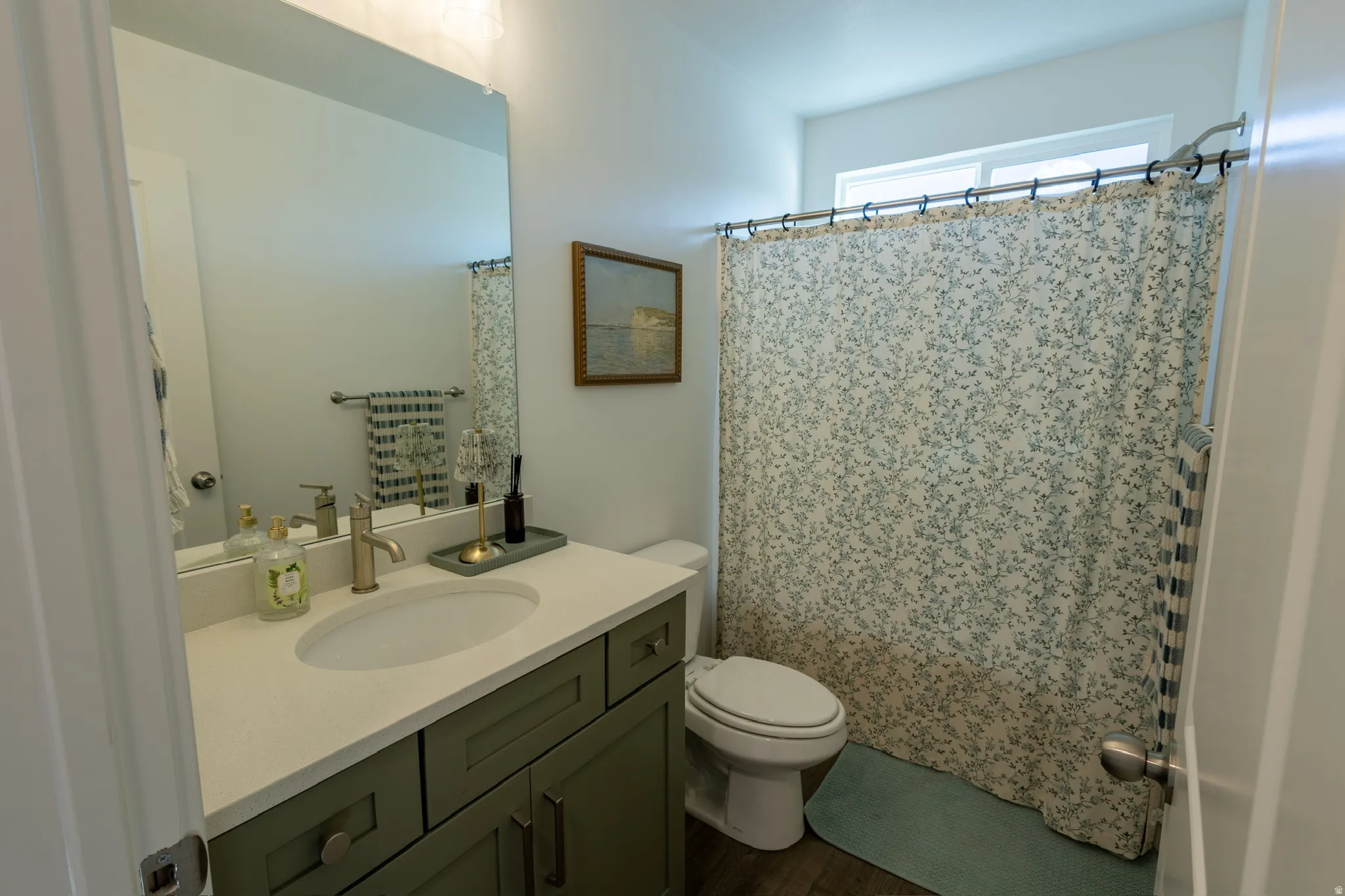 Vanity with a light-colored countertop, undermount sink, and brushed brass-finish faucet