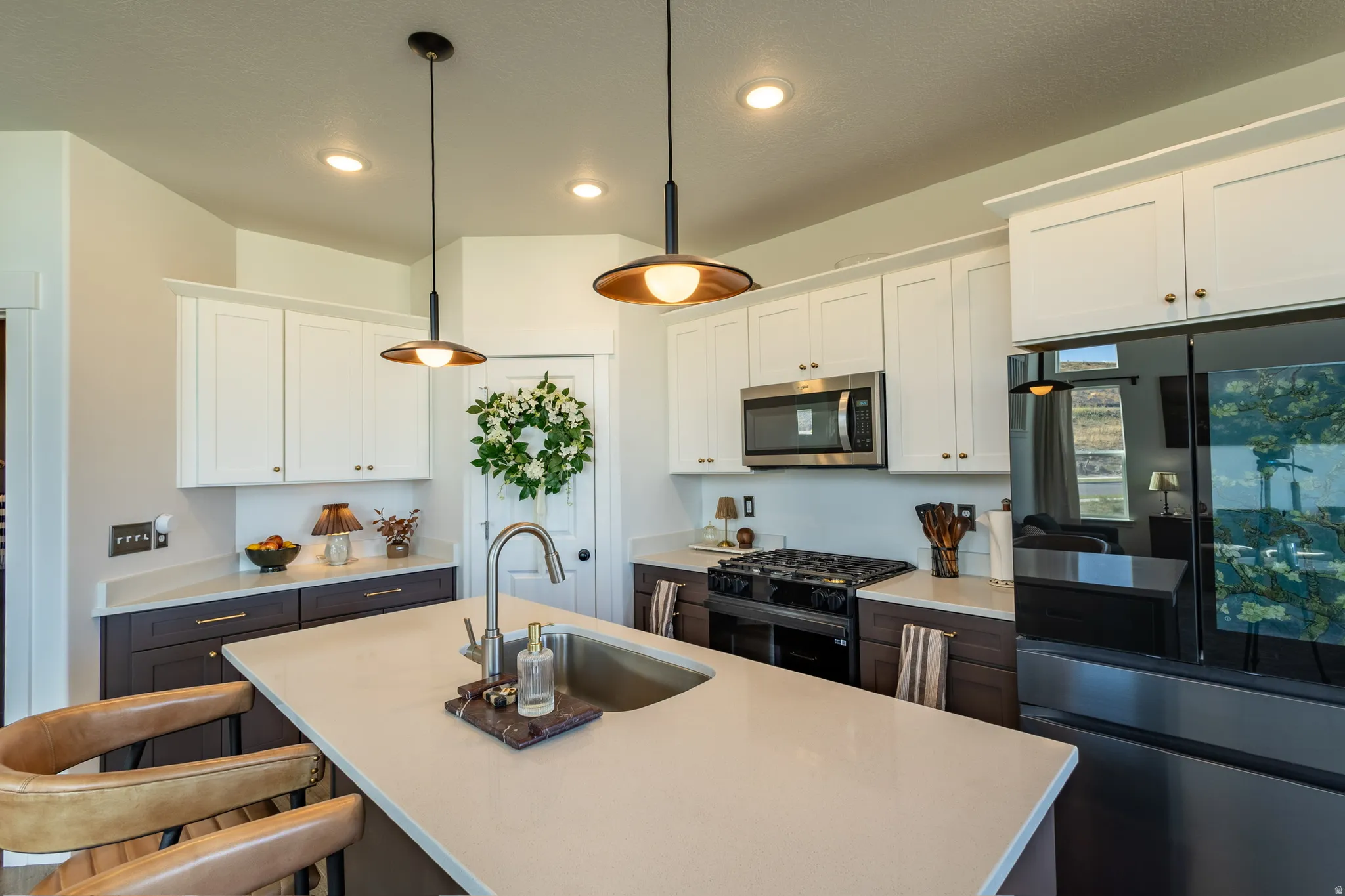 Gourmet kitchen featuring a peninsula island with an undermount sink, stainless steel appliances, two-tone cabinetry, and recessed lighting