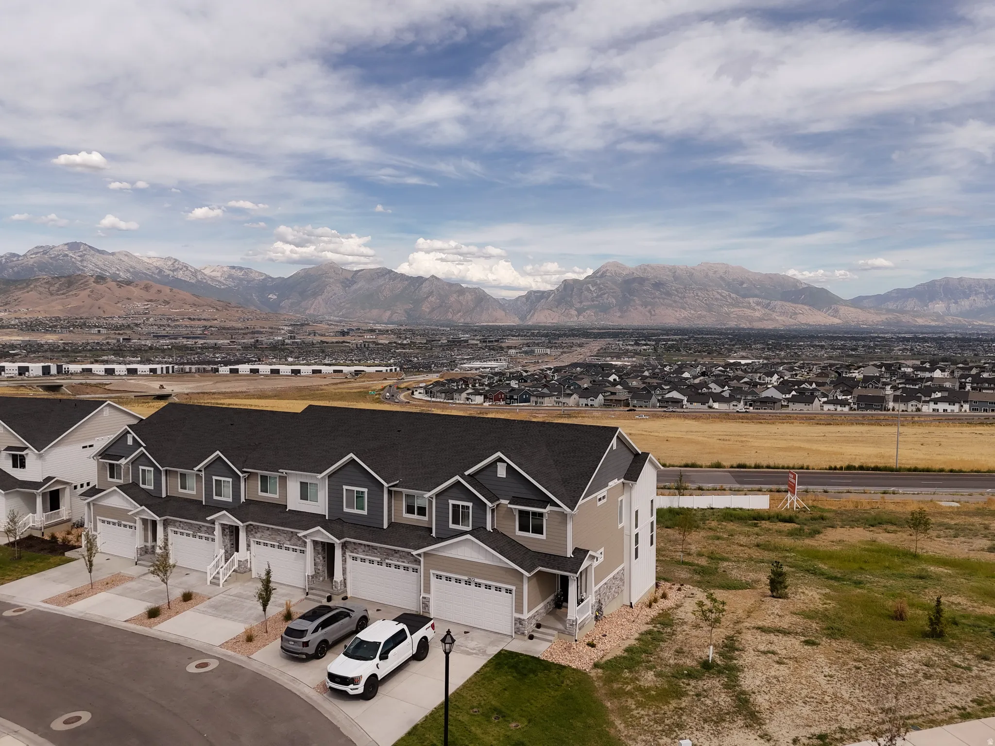 Contemporary townhome designs featuring stone and siding exteriors, attached garages, and a mountain backdrop