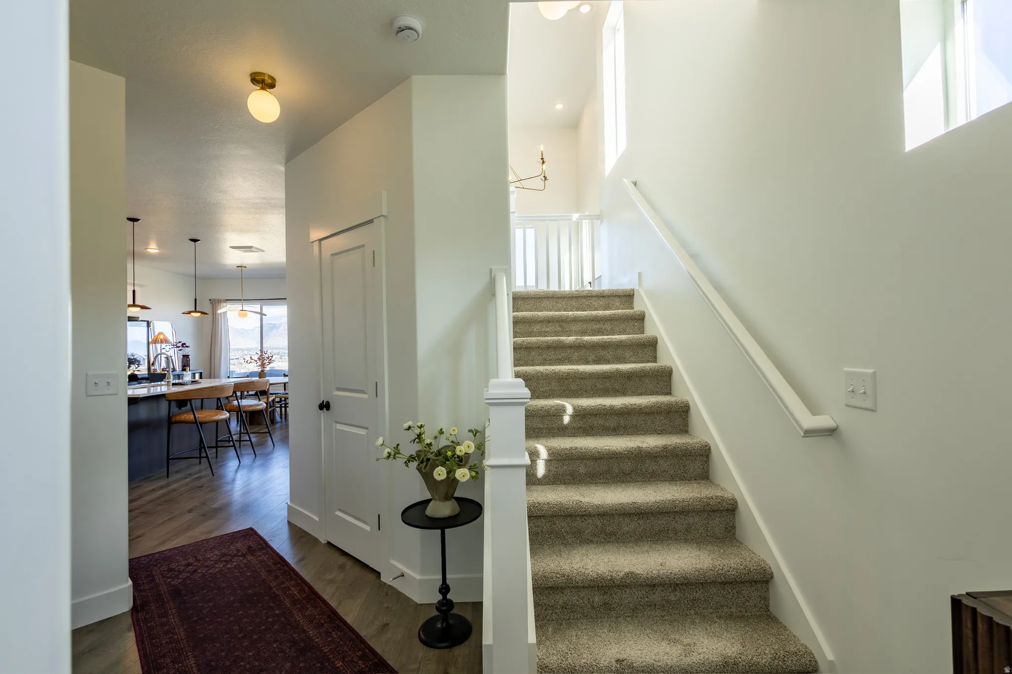 Carpeted staircase with white railing, wood-finish flooring, and bright white walls