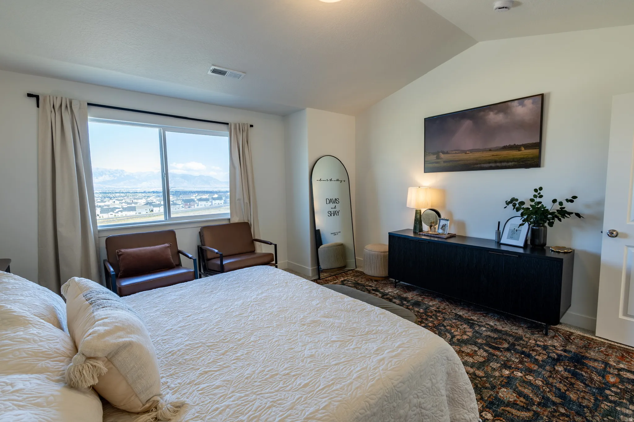 Vaulted ceiling, wide window with expansive mountain scenery, and light-colored walls
