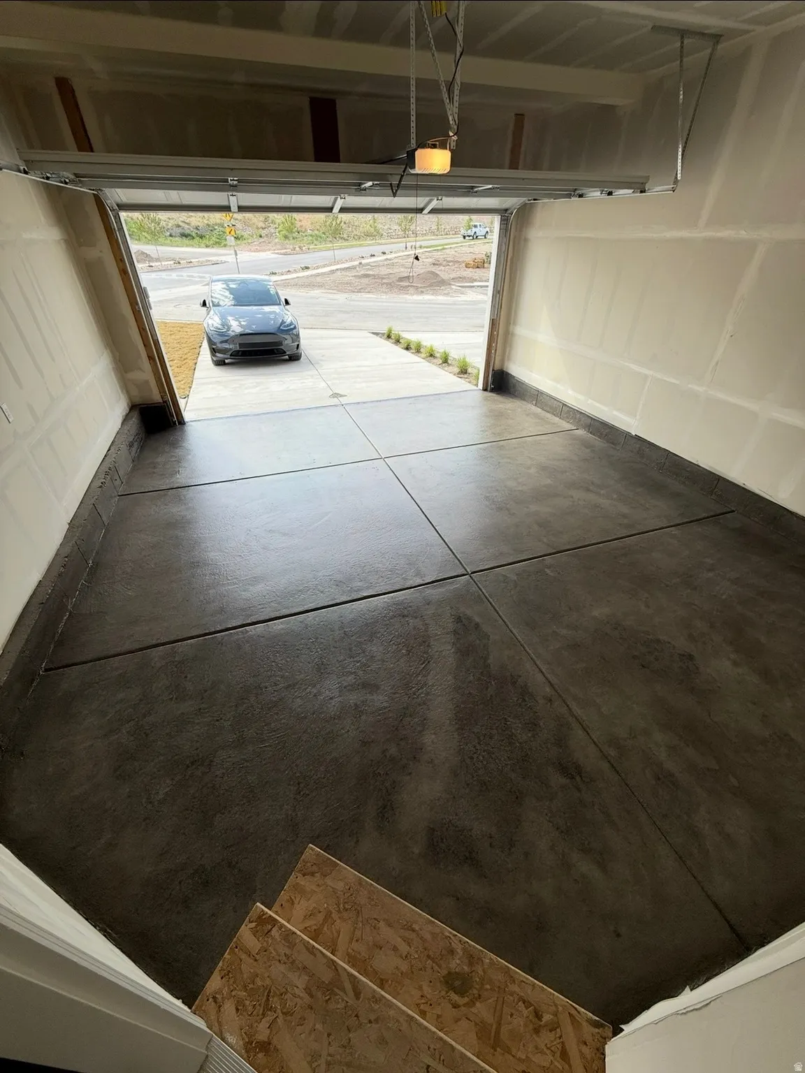 Garage with a stained and sealed concrete floor, automatic door opener, and drywall walls