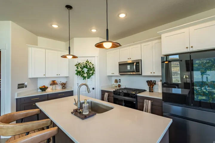 Gourmet kitchen featuring a peninsula island with an undermount sink, stainless steel appliances, two-tone cabinetry, and recessed lighting