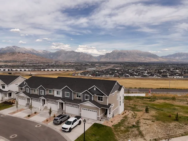 Contemporary townhome designs featuring stone and siding exteriors, attached garages, and a mountain backdrop