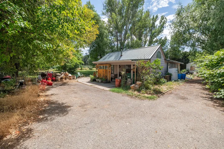 Gravel drive with a detached structure featuring a metal roof and arched window
