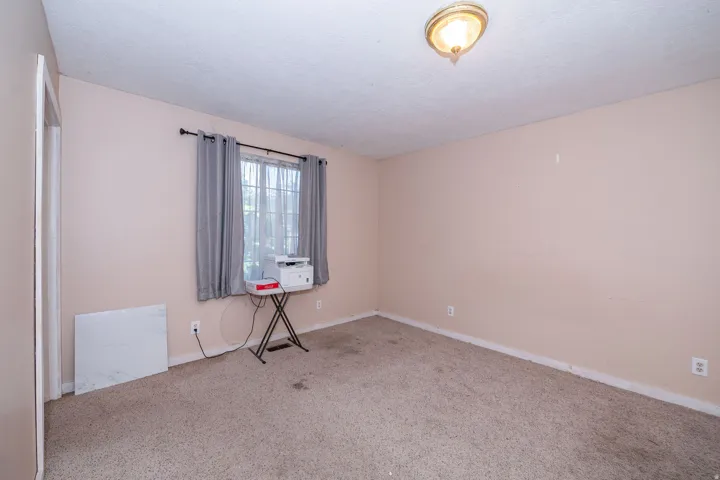 Recessed window with natural light, wall-mounted light fixture, and carpeted flooring