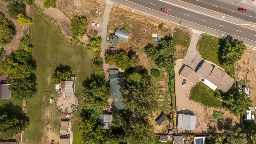 Spacious property featuring multiple structures, extensive green space, a paved driveway, and mature trees