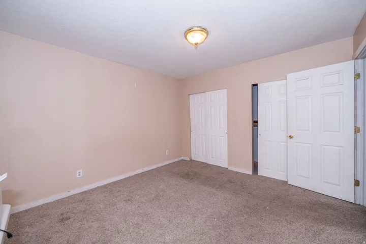 Wall-to-wall carpeting, neutral wall color, ceiling-mounted light fixture, and white bi-fold closet doors