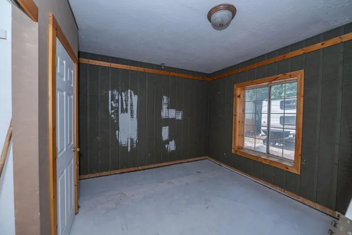 Wood-paneled wall accents, natural wood window trim, panel door, and flush-mount ceiling light fixture