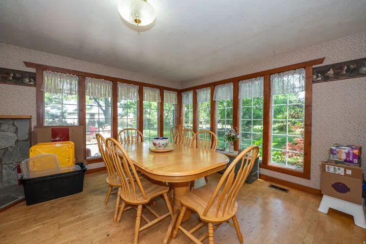 Large pane windows with wood trim, light wood-finish flooring, and a stone-clad architectural feature