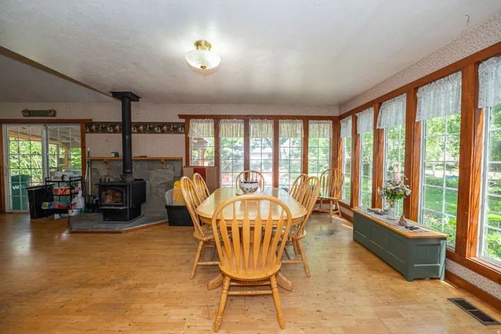 Wood-finish flooring, full-wall windows with wood trim, built-in stone fireplace, and sliding glass doors