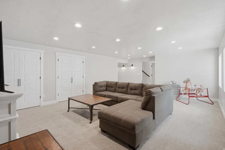 Recessed ceiling lighting, light gray wall tones, two white paneled doors with modern hardware, and a neutral carpeted floor