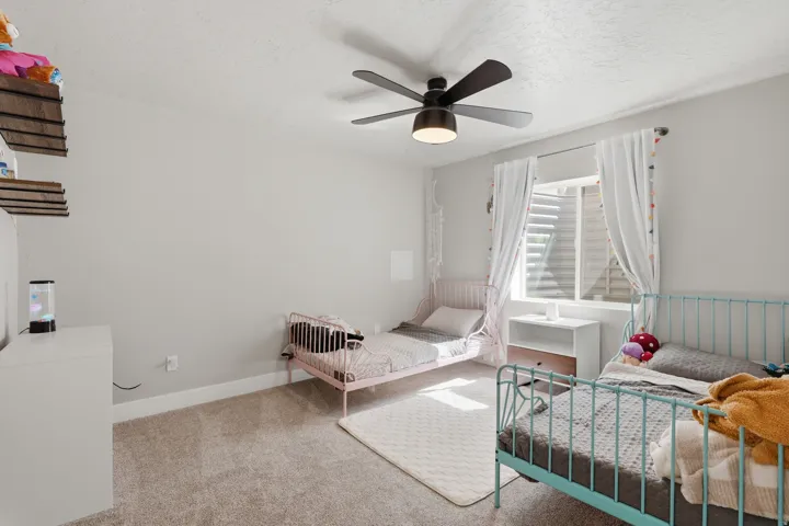 Carpeted room with a ceiling fan, recessed window, and wall-mounted shelving