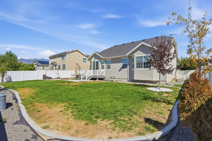 Expansive backyard featuring a manicured lawn, established trees, and a white privacy fence