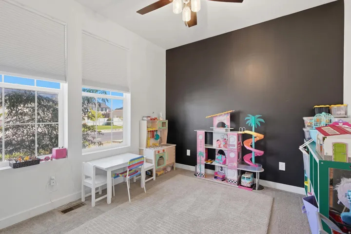 Room featuring two large windows, a dark accent wall, and a ceiling fan with integrated lighting