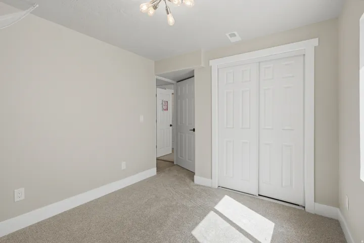 Neutral-toned walls, light-colored carpet flooring, white trim, and a decorative ceiling light fixture