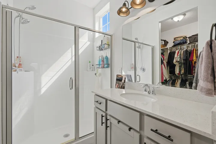 Walk-in shower with clear glass enclosure, dual shower heads, and white tile surround