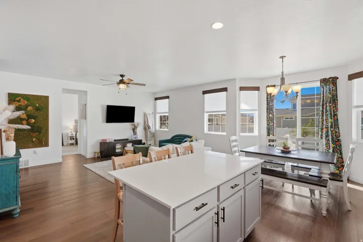 Open-concept living space with wood-finish flooring, white walls, and recessed lighting