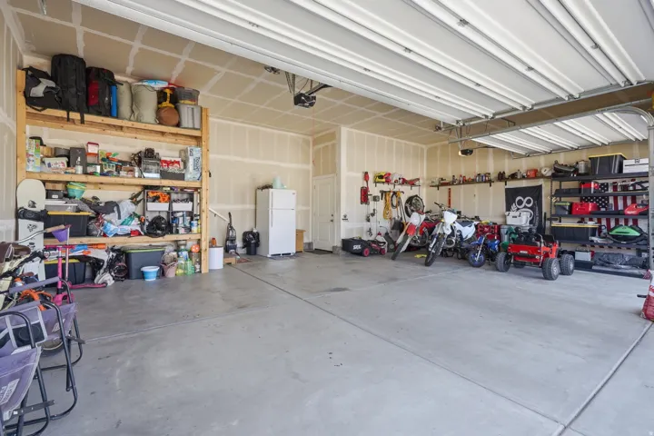 Spacious garage featuring a concrete floor, exposed drywall, and overhead garage door system