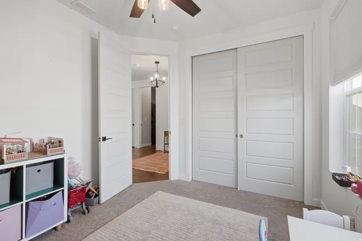 Neutral wall color, ceiling fan, white paneled doors, sliding closet doors, window with blinds