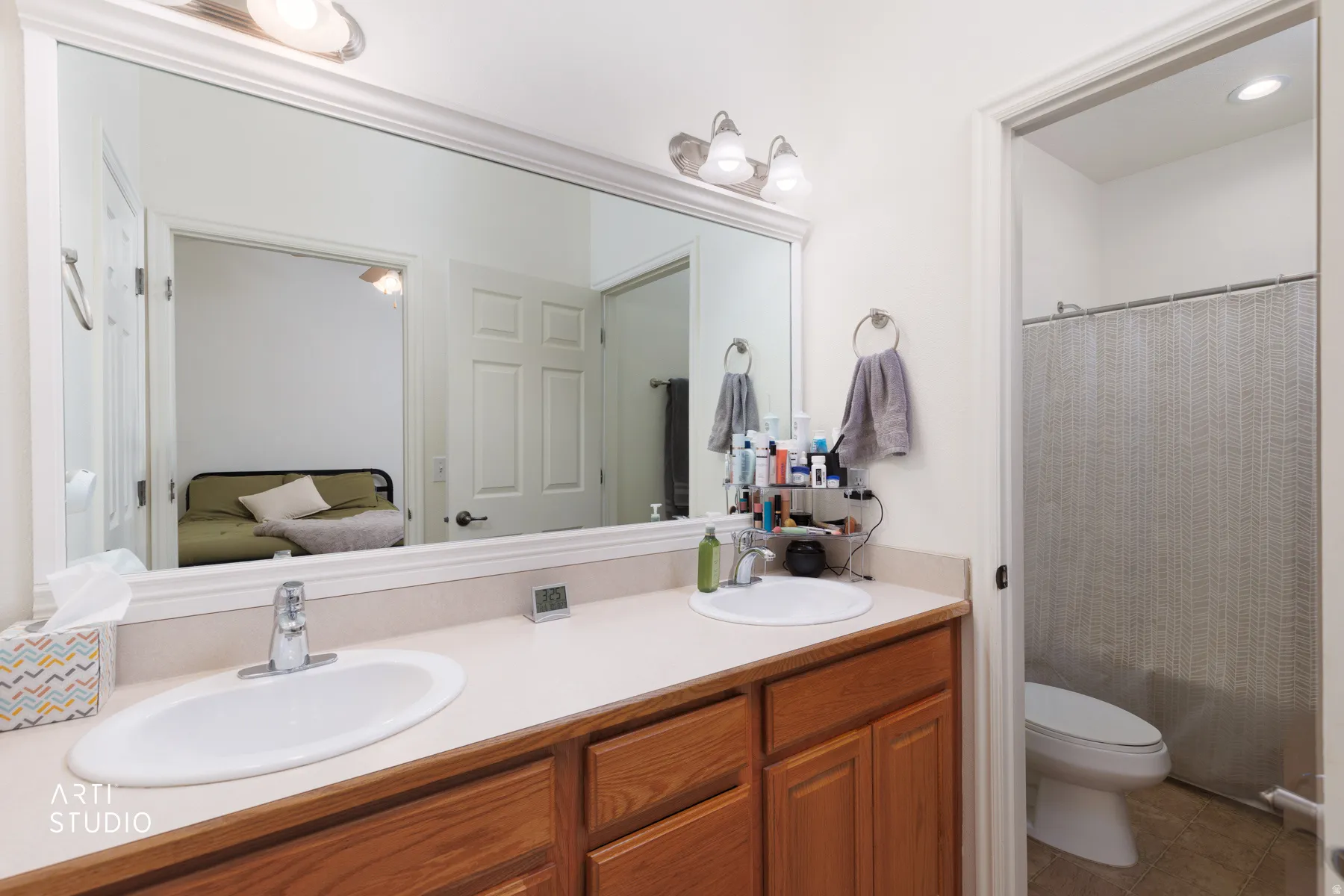 Dual undermount sinks with chrome fixtures, wood-finish cabinetry, and a large vanity mirror