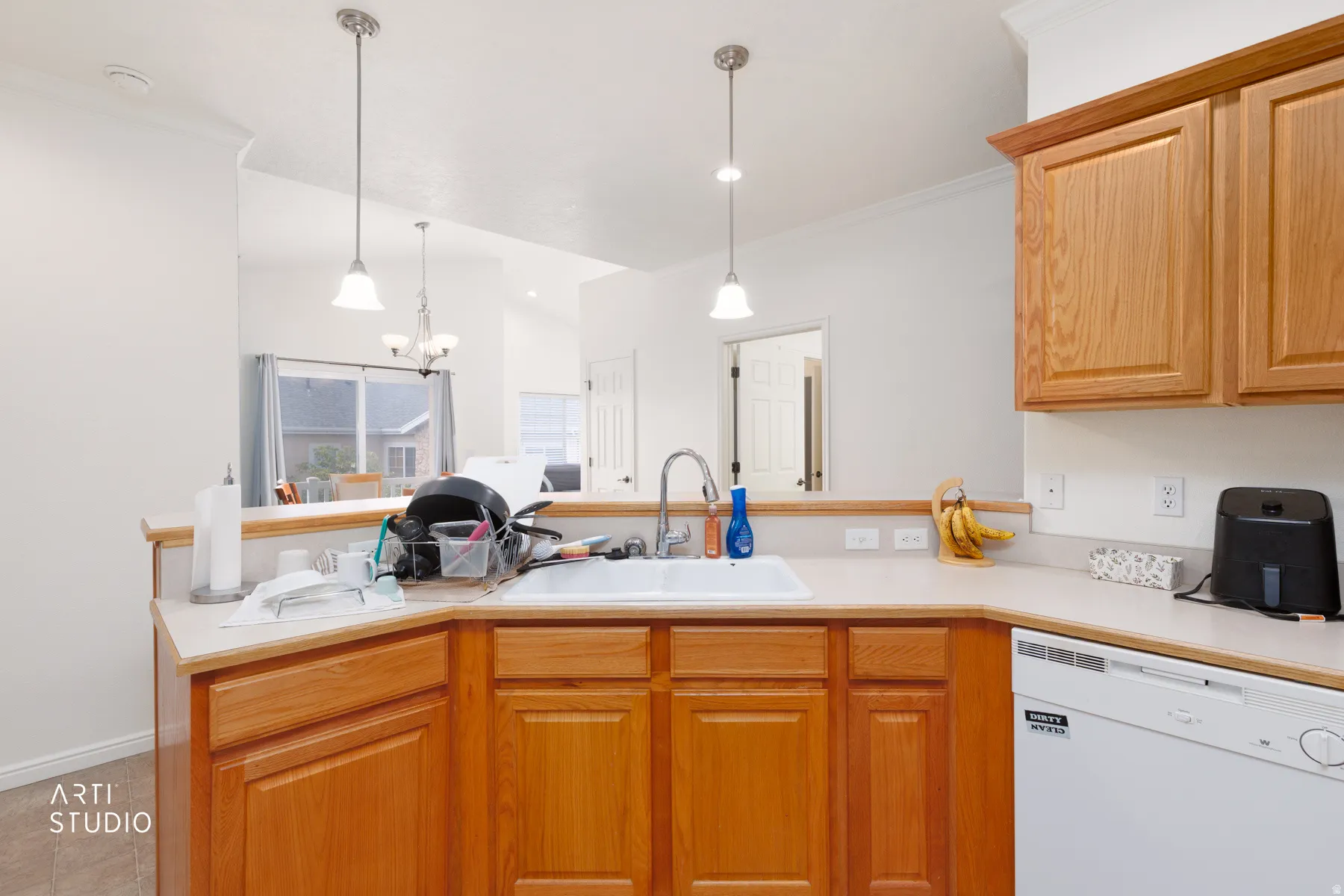 Wood-finish cabinetry paired with light-toned countertops, white sink, and stainless steel faucet