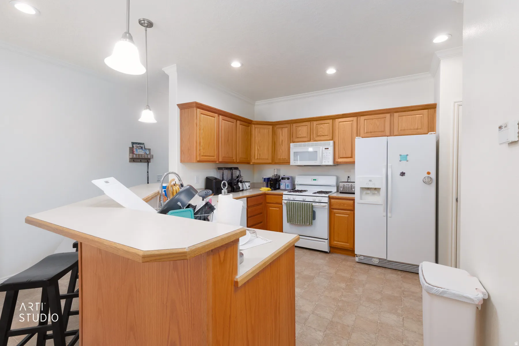 Kitchen featuring wood-finish cabinetry, white appliances, recessed lighting, and a breakfast bar with pendant lights