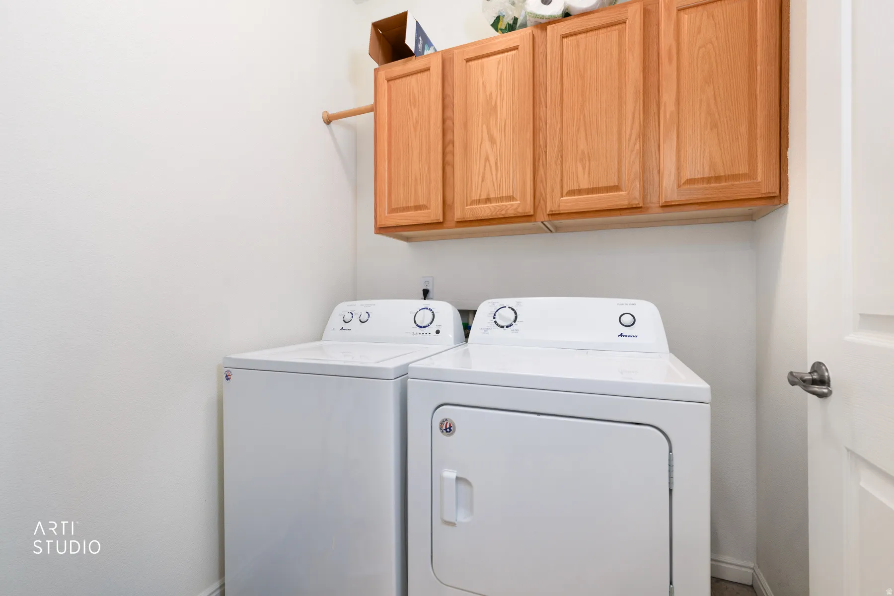 Laundry area featuring wood-finish cabinetry and a clothes hanging rod