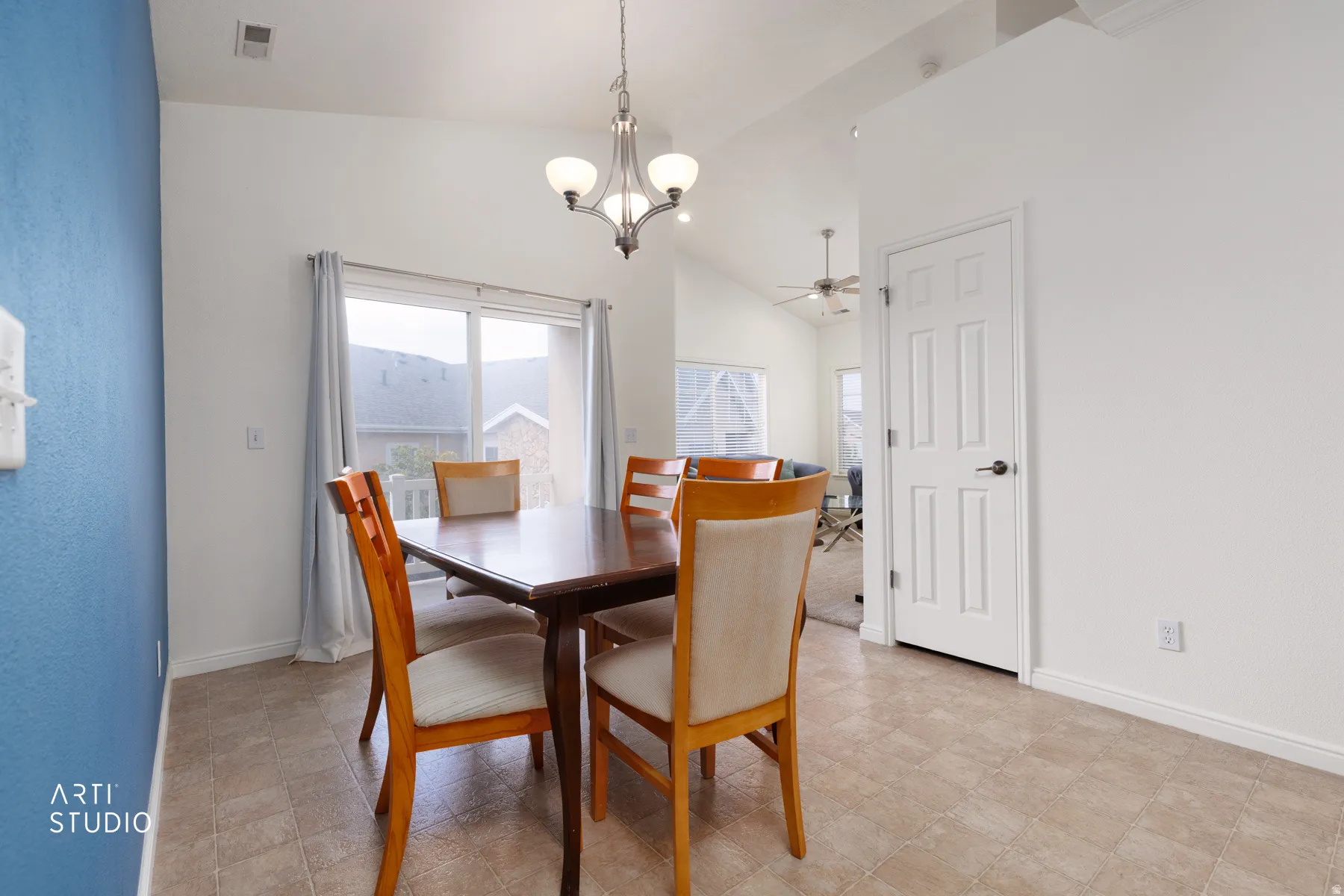 Vaulted ceiling with an attached chandelier, sliding glass door, white paneled interior door, and neutral-toned flooring