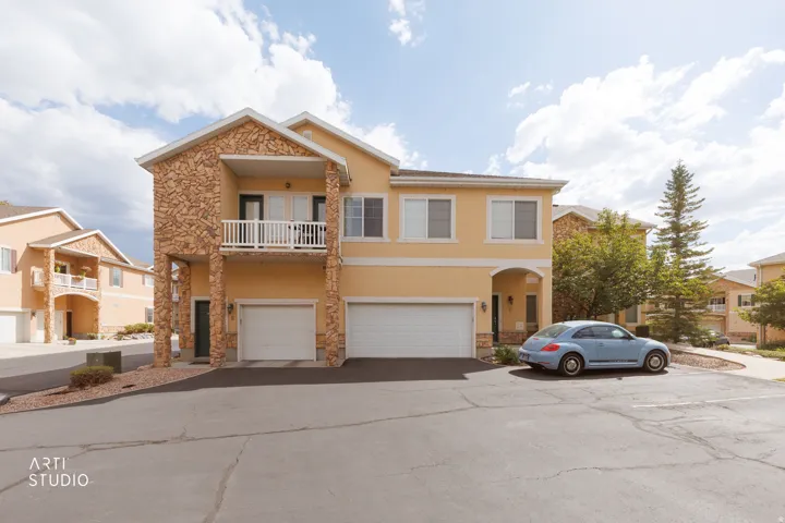Stucco exterior with stone accents, featuring a private balcony, arched entry, and two garage doors