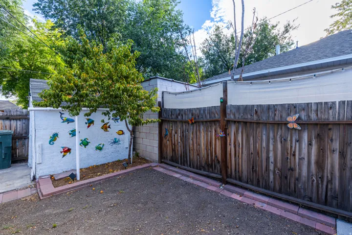 Private yard space featuring a wood fence, concrete block wall, and mature trees