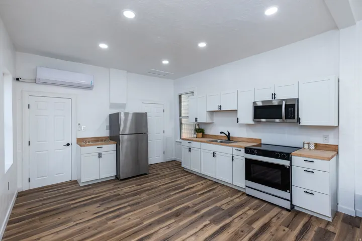 Updated kitchen featuring white shaker-style cabinetry, wood-finish countertops, and stainless steel appliances