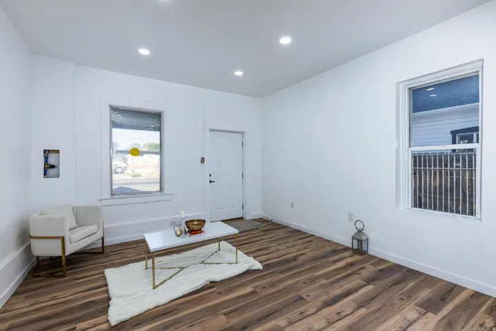 Open concept room featuring wood-finish flooring, white painted walls, recessed ceiling lighting, and a white paneled door