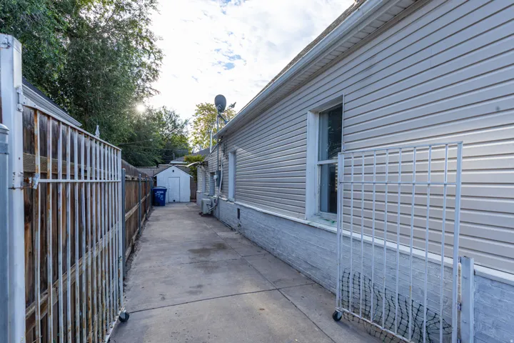 Gated concrete driveway with a privacy fence, leading to a detached shed
