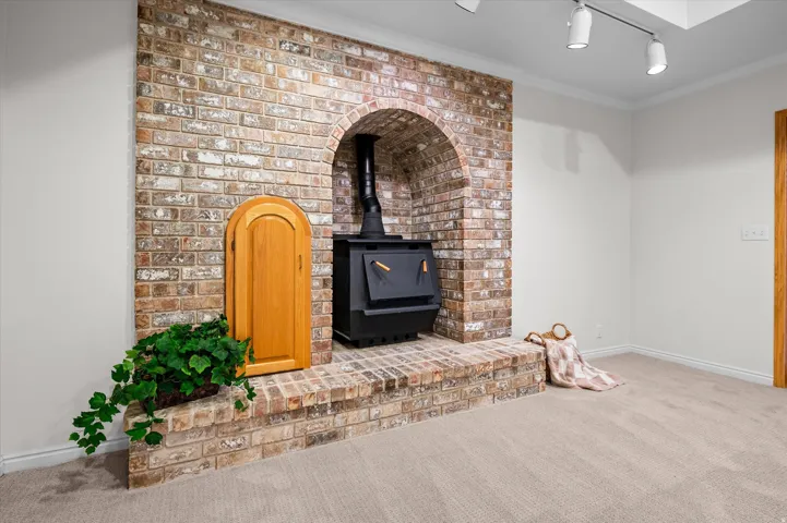 Brick accent wall featuring an arched opening and a wood-burning stove